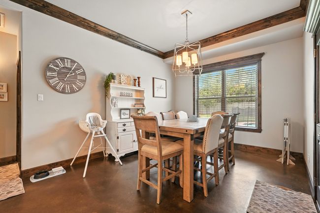 Dining space with concrete flooring and a chandelier | Image 9