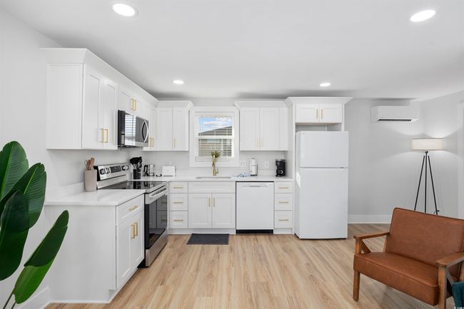 Kitchen with stainless steel appliances, a sink, a wall unit AC, white cabinets, and recessed lighting | Image 36