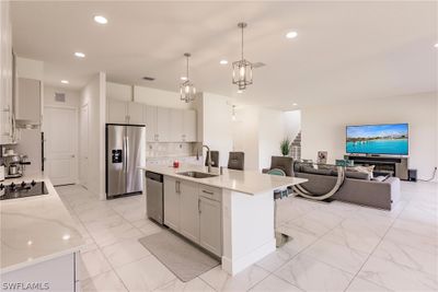 Kitchen featuring appliances with stainless steel finishes, an island with sink, backsplash, sink, and light tile floors | Image 3