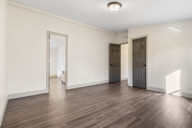 The primary bedroom offers a peaceful retreat with a serene view of the wooded front yard and the convenience of a private en-suite bathroom, creating a comfortable and relaxing space to unwind. | Image 12