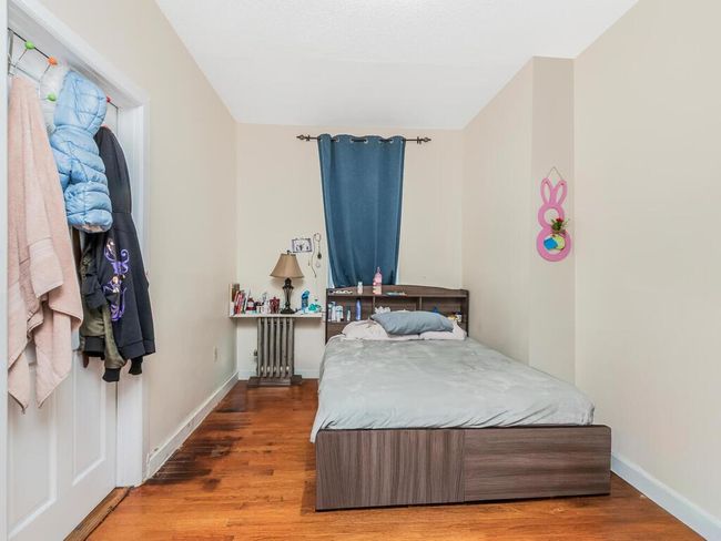 Bedroom with radiator heating unit, baseboards, and wood finished floors | Image 8