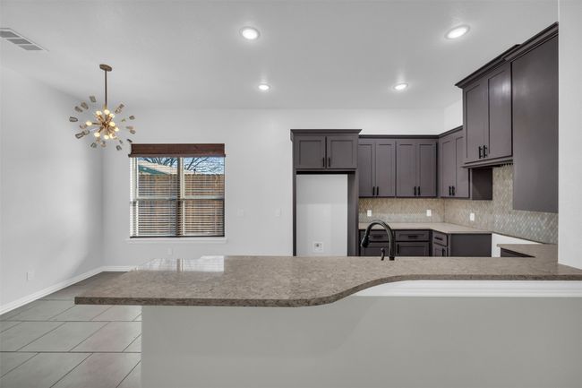 Kitchen featuring decorative light fixtures, kitchen peninsula, sink, and decorative backsplash | Image 16