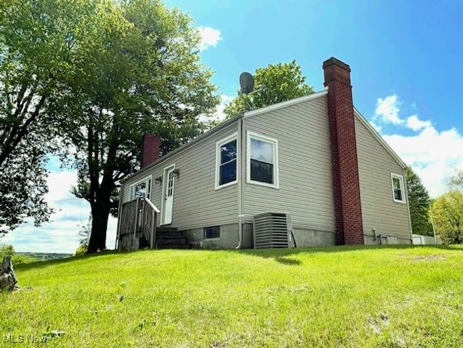 View of property exterior with a chimney, a yard, and central AC unit | Image 6