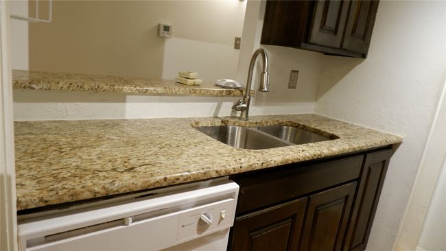 Kitchen featuring dishwasher, granite counters, dark brown cabinetry, and sink | Image 4