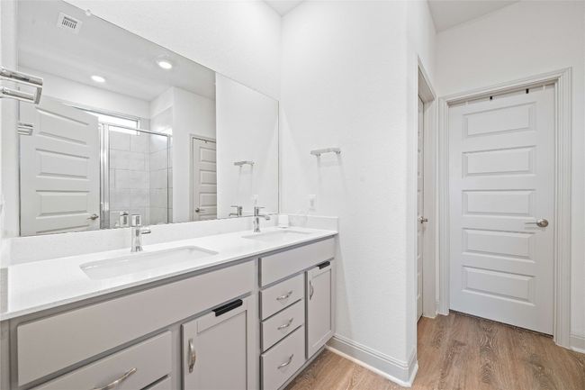 Bathroom featuring a shower stall, visible vents, wood finished floors, a sink, and double vanity | Image 22