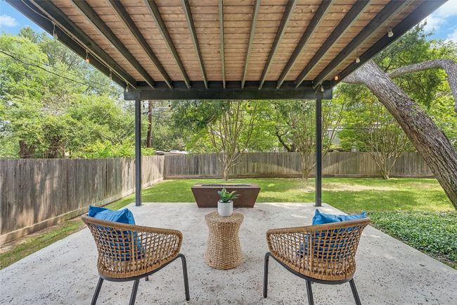 Your living area extends outdoors onto this serene covered patio addition with steel posts and beams and a built-in gas fire pit, perfect for year round outdoor entertainment. | Image 32