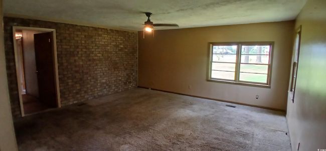 Unfurnished room featuring a ceiling fan, carpet, and brick wall | Image 22