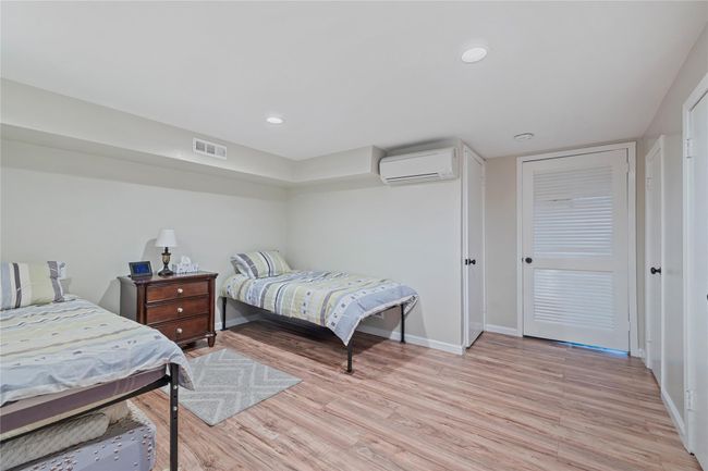 Bedroom featuring an AC wall unit, baseboards, visible vents, and light wood-style flooring | Image 35