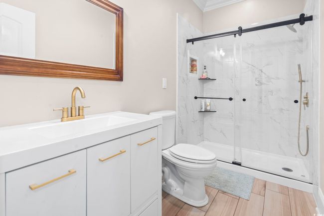 Full bath featuring toilet, a marble finish shower, crown molding, vanity, and wood finished floors | Image 23