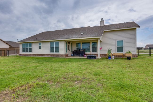 Rear view of property featuring a fenced backyard, a chimney, brick siding, roof with shingles, and a patio area | Image 20