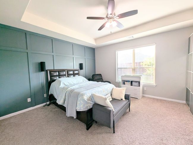 Bedroom with a tray ceiling, light carpet, a decorative wall, and a ceiling fan | Image 34