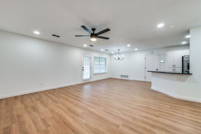 Unfurnished living room with light wood-style flooring, ceiling fan with notable chandelier, visible vents, and recessed lighting | Image 8