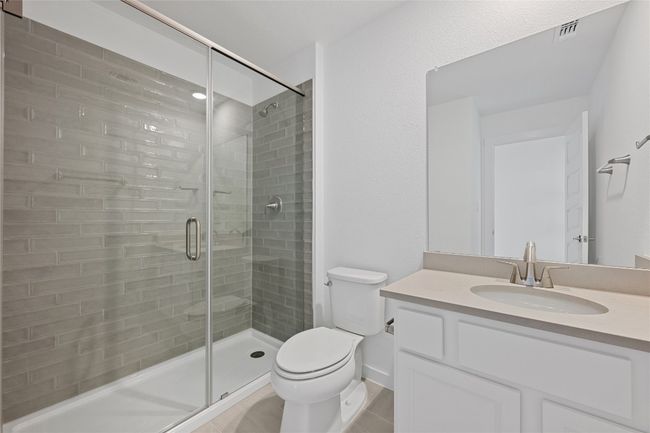 Full bath featuring toilet, a shower stall, vanity, and tile patterned flooring | Image 23
