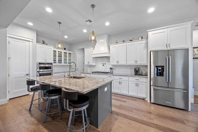 Elegant gourmet kitchen, ideal for entertaining, overlooks the living area. It includes custom cabinetry with soft-close drawers, top-tier KitchenAid appliances, a pot filler over the gas cooktop, a spacious walk-in pantry, and a deep stainless farmhouse sink with a designer faucet, complemented by a stylish vent hood. | Image 15