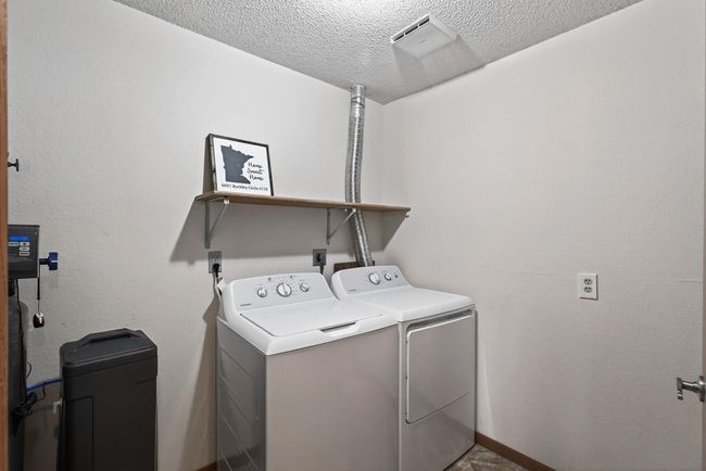 The laundry room includes a a new washer and dryer set that were installed in 2023. The new Culligan water softener was installed in 2022. Just behind the door you will find built-in shelving for additional storage space. | Image 18