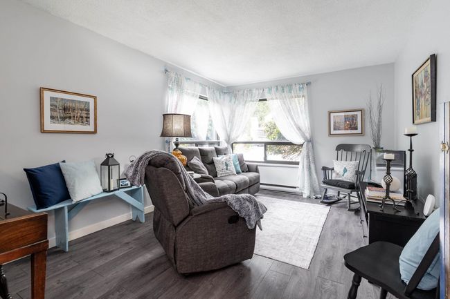 Living area with a baseboard heating unit, wood finished floors, baseboards, and a textured ceiling | Image 10