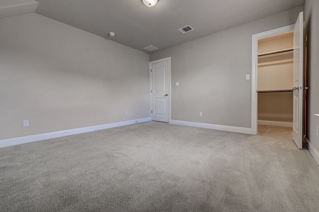 Unfurnished bedroom featuring a spacious closet, carpet, vaulted ceiling, and a closet | Image 25