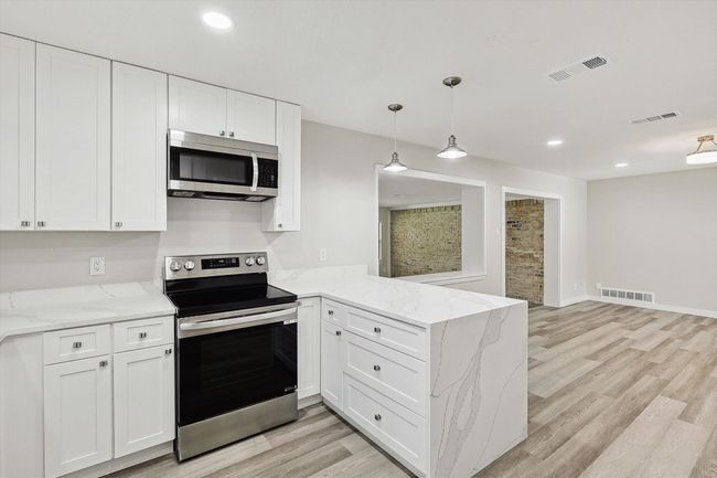Kitchen featuring visible vents, a peninsula, and stainless steel appliances | Image 11