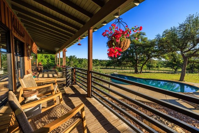 Wooden deck with an outdoor pool and view of wooded area | Image 13