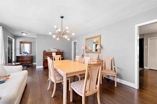 Dining space with a chandelier, dark wood finished floors, and baseboards | Image 9