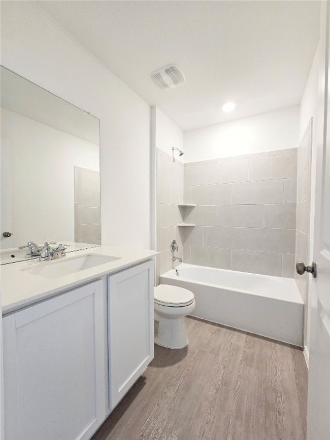 Bathroom featuring wood finished floors, toilet, vanity, and washtub / shower combination | Image 29