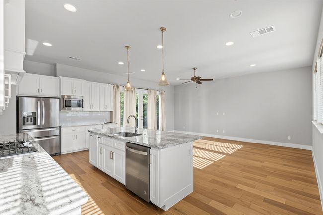 Kitchen with appliances with stainless steel finishes, a sink, a ceiling fan, backsplash, and white cabinets | Image 4