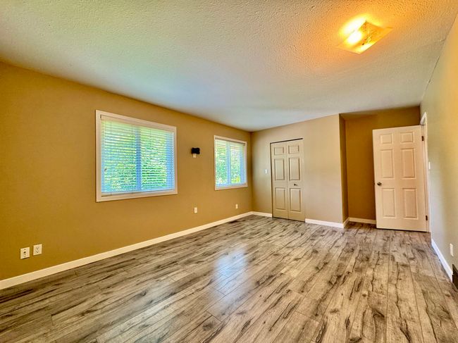 Unfurnished bedroom featuring wood finished floors, a textured ceiling, and a closet | Image 12