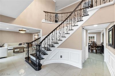 Stairs with an inviting chandelier, a high ceiling, tile patterned floors, and crown molding | Image 2