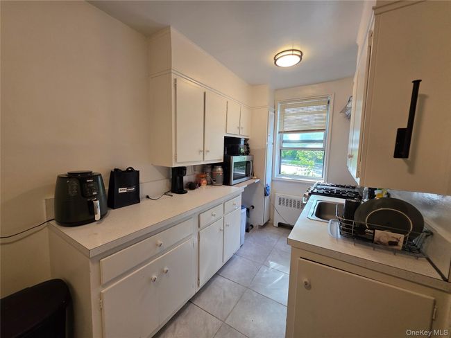 Kitchen featuring radiator, light countertops, white cabinetry, and light tile patterned floors | Image 6
