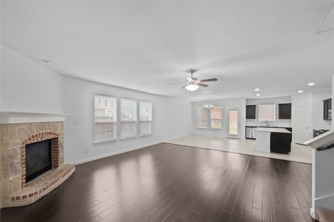 Unfurnished living room with a fireplace, recessed lighting, ceiling fan, wood finished floors, and a chandelier | Image 9