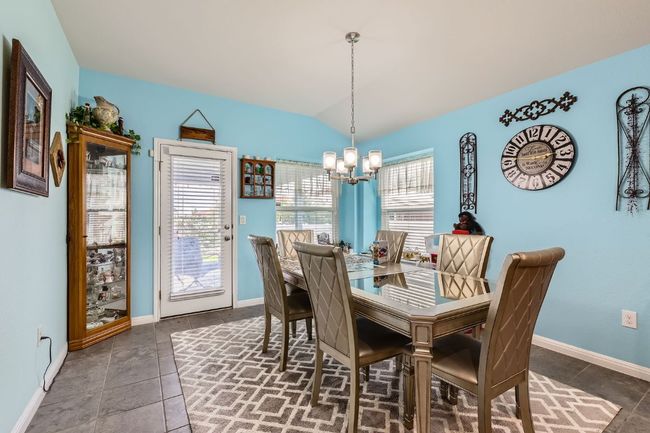 Dining room featuring an inviting chandelier, tile patterned floors, vaulted ceiling, and baseboards | Image 8