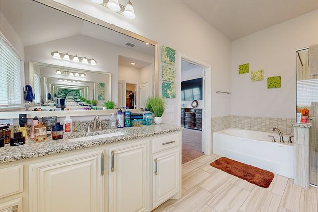 Bathroom with vanity, lofted ceiling, a garden tub, and visible vents | Image 36