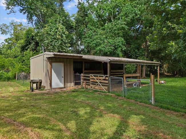 Metal barn with covered stalls and fenced enclosure, ideal for goats or small animals. | Image 42
