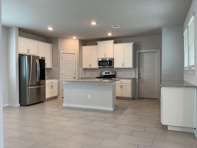 Kitchen featuring appliances with stainless steel finishes, backsplash, recessed lighting, and white cabinetry | Image 8