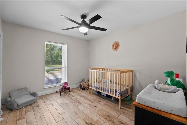 Peaceful bedroom with large window for front yard views, modern ceiling fan, and neutral tones. | Image 30