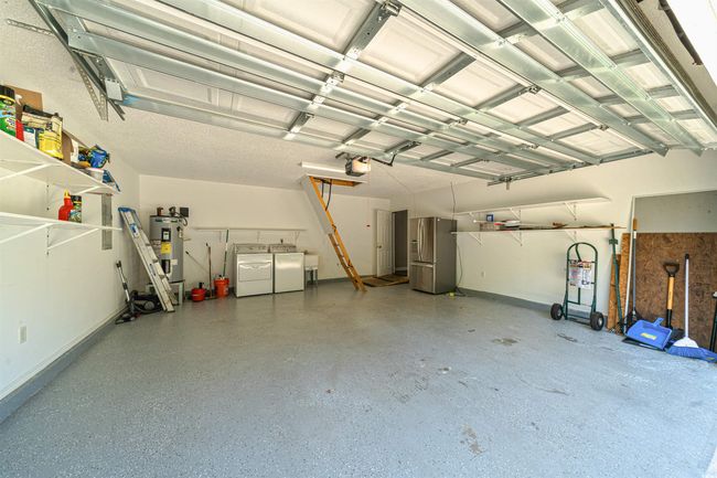 Garage with independent washer and dryer, a garage door opener, water heater, baseboards, and stainless steel refrigerator with ice dispenser | Image 39
