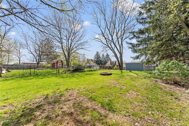 View of yard with an outdoor structure, a fire pit, and fence | Image 8