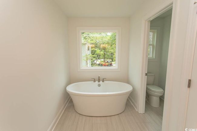 Bathroom featuring a freestanding tub, toilet, and baseboards | Image 29