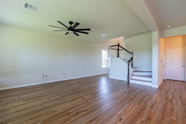 Unfurnished living room with wood finished floors, stairs, and ceiling fan | Image 5