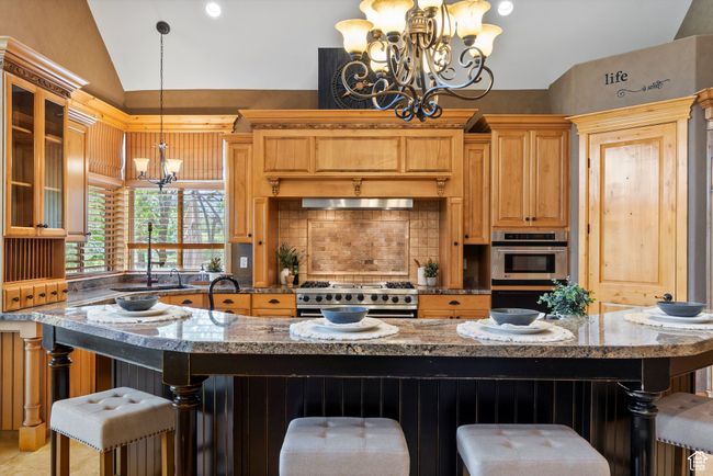 Kitchen featuring a chandelier, vaulted ceiling, appliances with stainless steel finishes, tasteful backsplash, and glass insert cabinets | Image 34