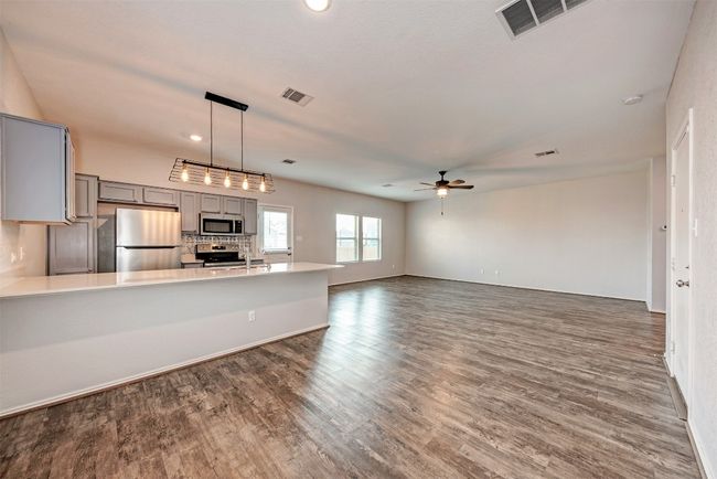 Kitchen featuring gray cabinets, appliances with stainless steel finishes, ceiling fan, a peninsula, and dark wood-style floors | Image 9