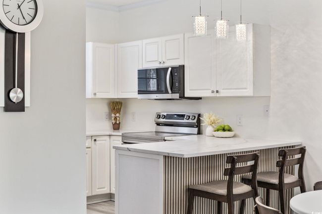 Kitchen featuring appliances with stainless steel finishes, white cabinets, a kitchen breakfast bar, and crown​​‌​​​​‌​​‌‌​‌‌​​​‌‌​​‌‌​‌​​​​​‌ molding | Image 12