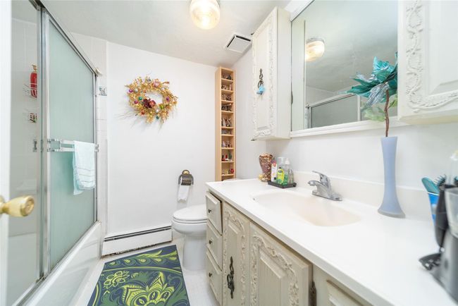 Bathroom featuring vanity, baseboard heating, enclosed tub / shower combo, toilet, and visible vents | Image 7