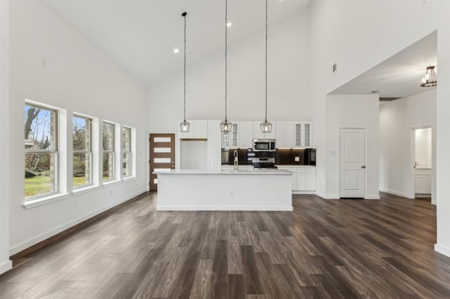 Kitchen featuring appliances with stainless steel finishes, high vaulted ceiling, glass insert cabinets, white cabinetry, and dark wood-style floors | Image 16