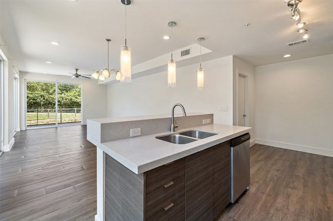 Kitchen with open floor plan, modern cabinets, dark wood-type flooring, a kitchen island with sink, and recessed lighting | Image 6
