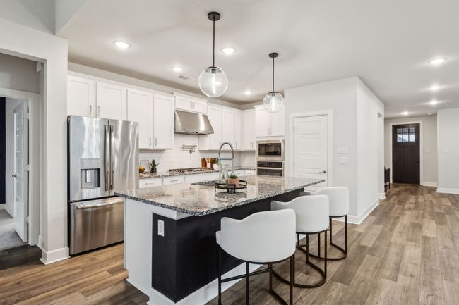 Kitchen with appliances with stainless steel finishes, under cabinet range hood, wood finished floors, backsplash, and recessed lighting | Image 4
