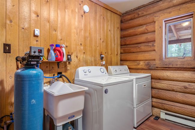 Laundry area featuring a baseboard heating unit, independent washer and dryer, rustic walls, and wood finished floors | Image 48