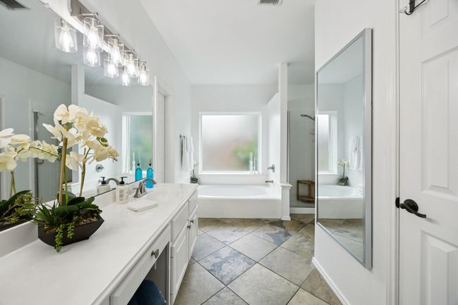 Light and bright bathroom featuring a garden tub, vanity, dual sinks, shower, and tile patterned floors | Image 19