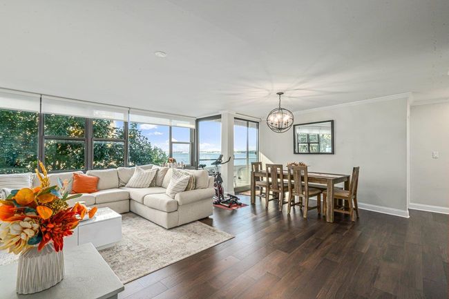 Living area featuring a chandelier, dark wood-style flooring, crown molding, and a water view | Image 9