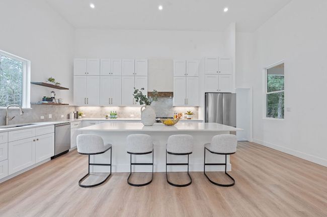 Kitchen with light quartz countertops, stainless steel appliances, a breakfast bar, and a sink | Image 12